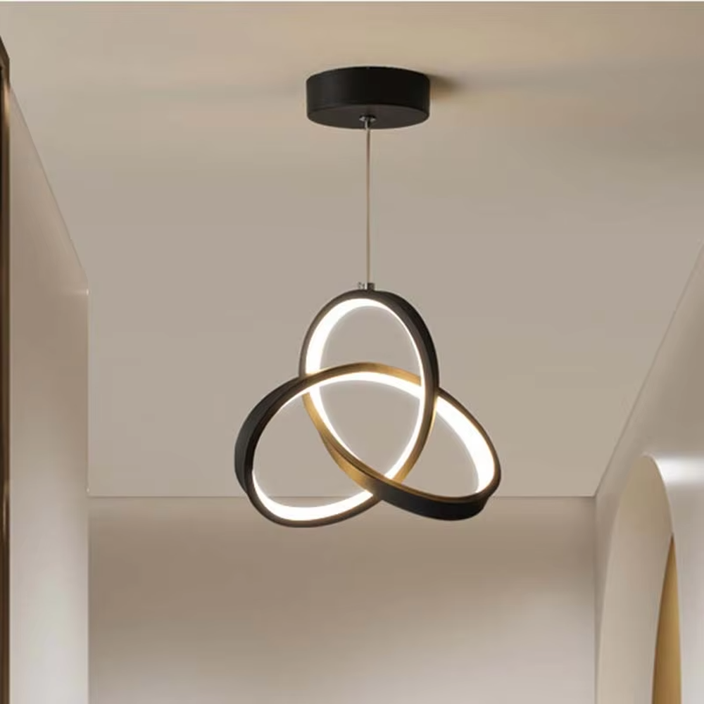 Modern minimalist black-gold interwoven triple-ring LED pendant light, warm light effect, creating a minimalist artistic space atmosphere.