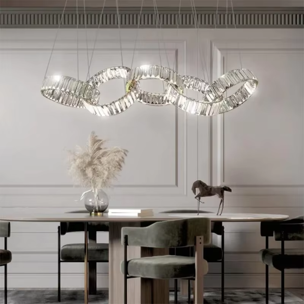 This is a modern light luxury style interlocking crystal chandelier, composed of transparent cut crystal strips forming a chain-like structure, paired with a gold metal suspension base. Light refracts through the crystals to create brilliant and dynamic lighting effects, serving both lighting and artistic decoration purposes, suitable for quality-focused scenarios such as large flat-floor dining rooms, villa living rooms, high-end clubs, and showrooms.