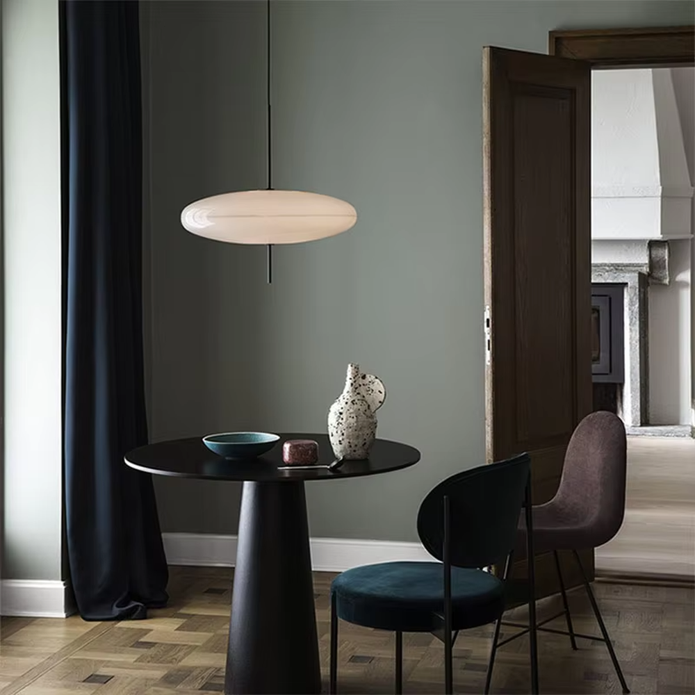 This modern minimalist flat round chandelier features a milky white frosted acrylic lampshade, paired with a thin black suspension rod, transmitting light softly. It serves both lighting and decorative purposes, ideal for modern minimalist spaces such as living rooms, bedrooms, and light luxury restaurants.