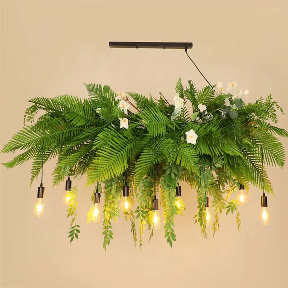 This is a natural and romantic floral retro chandelier, decorated with a large number of artificial flowers (pink and purple roses, etc.) and green plants (ferns, monstera leaves), paired with retro bulbs and a black metal frame. The design is natural and warm, with soft warm yellow lighting. It is used for space lighting and decoration, creating a natural romantic and warm retro atmosphere. Suitable for wedding venues, literary cafes, Nordic-style homestays, nature-themed restaurants and other places.