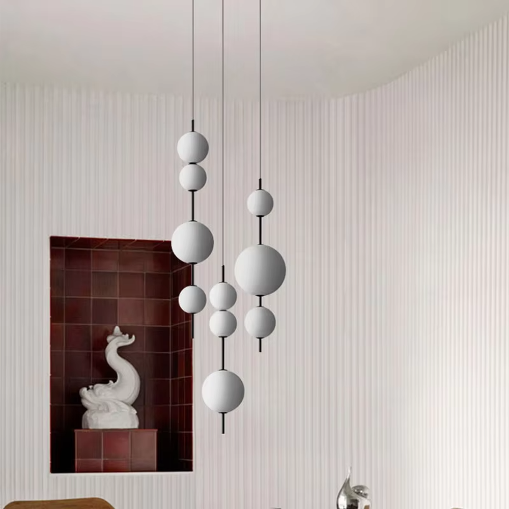 Modern tiered glass ball chandelier (black-white tiered balls + minimalist hanging rod), warm light effect, creating a simple and artistic space atmosphere.