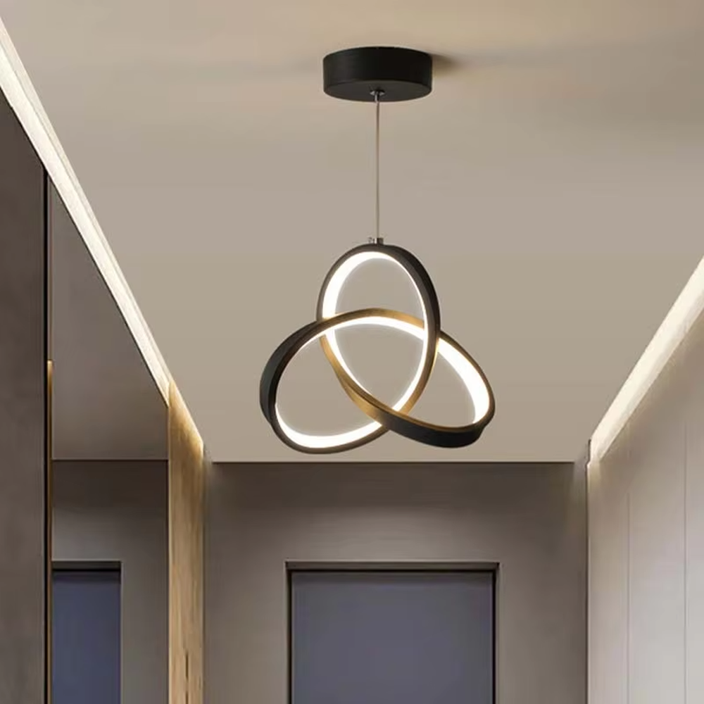 Modern minimalist black-gold interwoven triple-ring LED pendant light, warm light effect, creating a minimalist artistic space atmosphere.