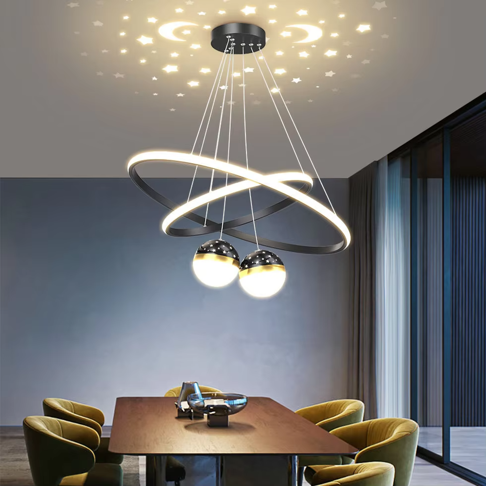 This is a modern creative cross-ring starry sky projection chandelier, with a black frame paired with cross-ring light strips and spherical lamps, and a starry sky (star and moon) projection function. The design is modern and dreamy, with soft lighting and a strong atmosphere. It is used for space lighting and atmosphere creation, suitable for modern-style living rooms, children's rooms, light luxury-style bedrooms and other places.