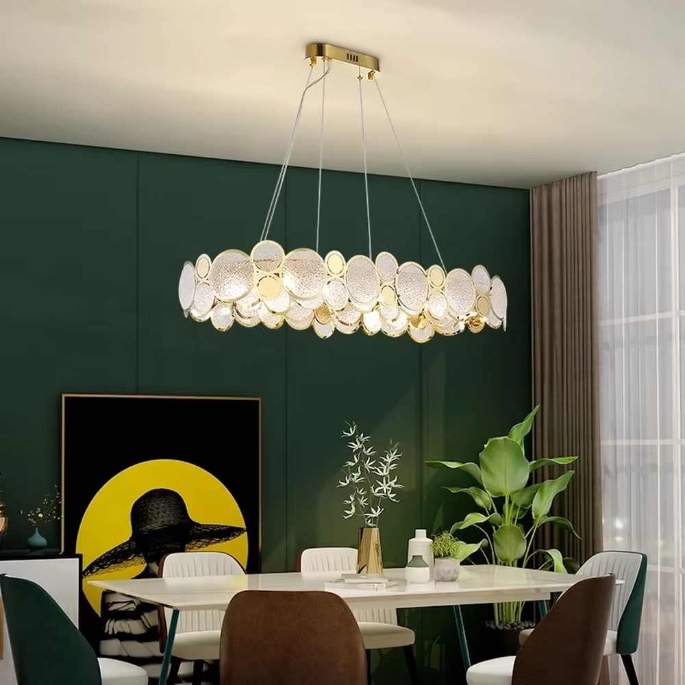 A modern light luxury style linear chandelier, featuring a gold metal frame with interlocked circular transparent glass panels and gold rings. It emits a brilliant yet soft glow when lit, combining decorative appeal with practical illumination, ideal for creating a sophisticated and high-end space atmosphere.