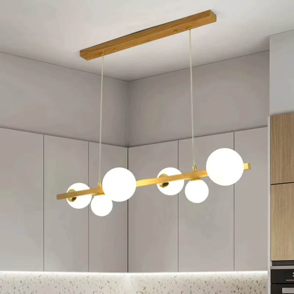 Nordic-style gold linear chandelier with a wood-like finish, paired with multiple round milk-white glass ball lampshades. It features a simple and lightweight design, emitting soft and gentle light, serving as a modern home lighting fixture that combines illumination and decoration.
