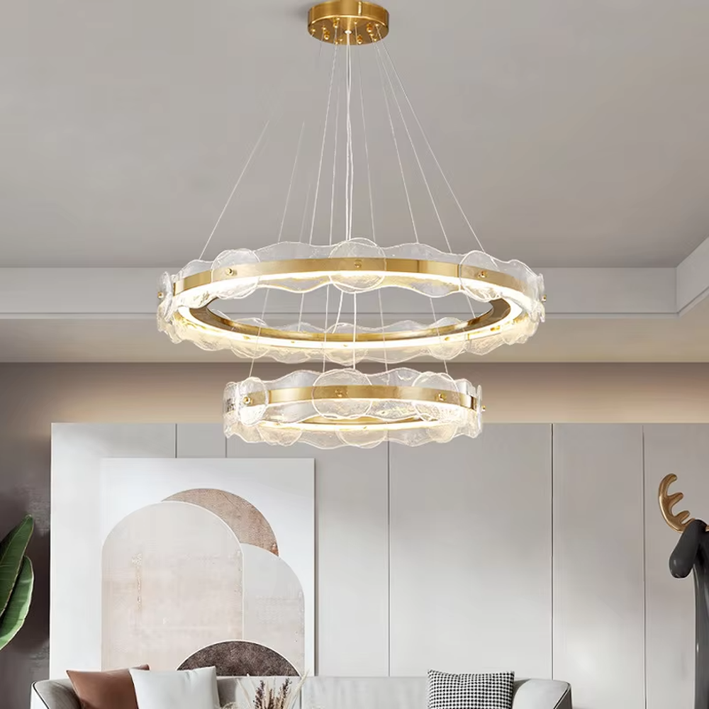 A modern light luxury style double-layer ring chandelier, featuring a gold metal frame paired with transparent glass panels with water ripple texture. It emits a soft and brilliant glow when lit, combining decorative appeal with practical illumination, ideal for creating a high-end and elegant space atmosphere.