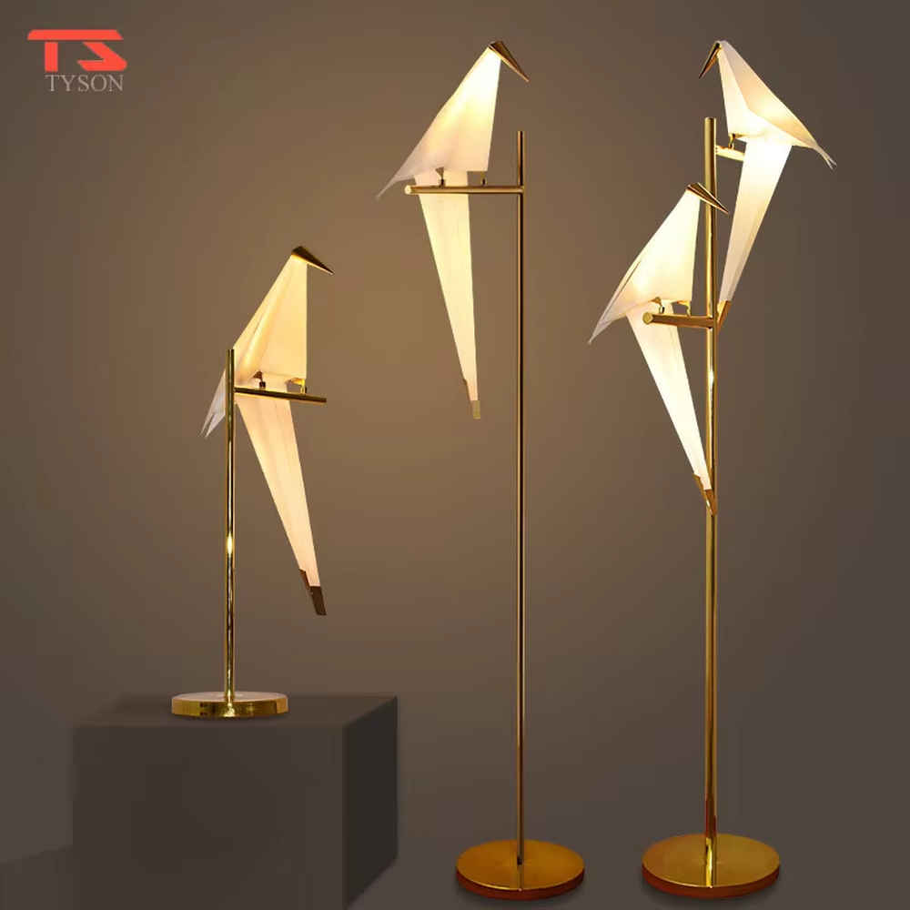 A modern art light luxury style origami crane chandelier, featuring a gold metal ring frame paired with an origami-style white translucent lampshade, shaped like an origami crane perched in a gold ring. It emits a soft and warm glow when lit, combining decorative appeal with practical illumination, ideal for creating an elegant and soothing space atmosphere.
