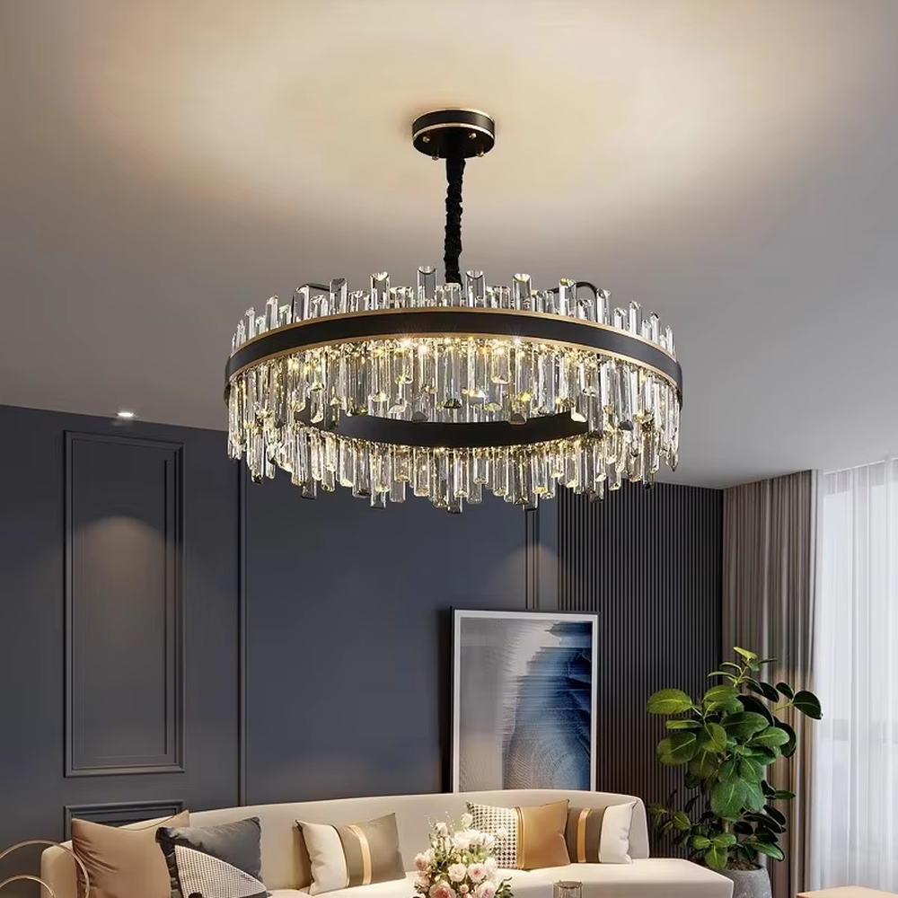 This light luxury black-gold double-layer round crystal chandelier features a black metal frame with crystal strips on the upper layer, and a gold frame with hanging faceted crystals on the lower layer. Light refracts through the crystals to emit a brilliant glow, serving both lighting and decorative purposes, suitable for modern light luxury spaces such as living rooms and dining rooms.