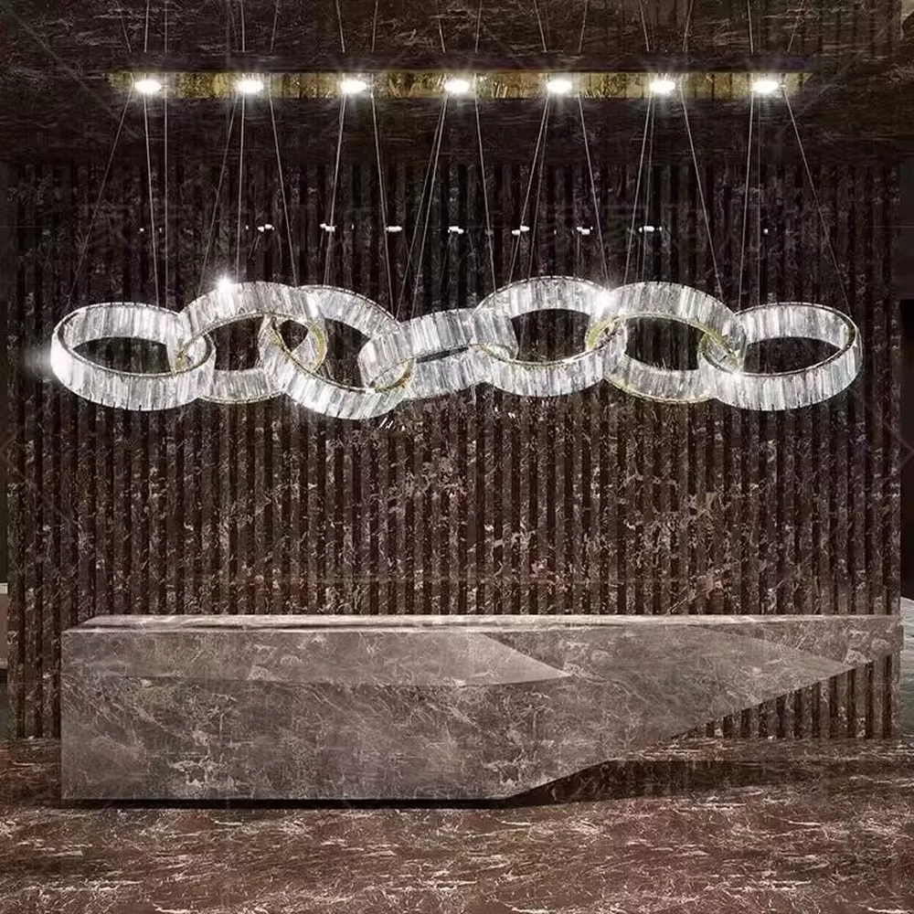Modern light luxury chain-style ring crystal chandelier, composed of multiple transparent crystal rings connected into a flexible chain shape, paired with metal suspension rods and a long top base, combining decorative and lighting functions, suitable for dining rooms, living rooms, villas and other light luxury style spaces.