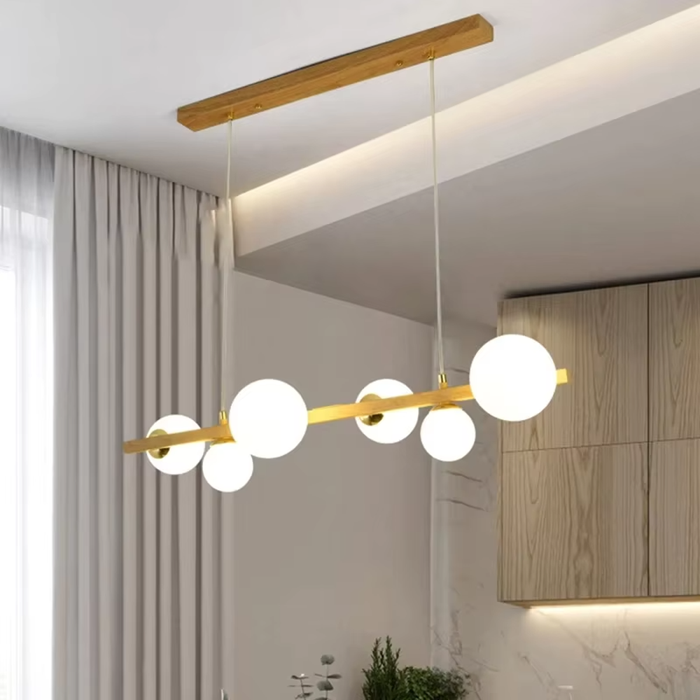 Nordic-style gold linear chandelier with a wood-like finish, paired with multiple round milk-white glass ball lampshades. It features a simple and lightweight design, emitting soft and gentle light, serving as a modern home lighting fixture that combines illumination and decoration.
