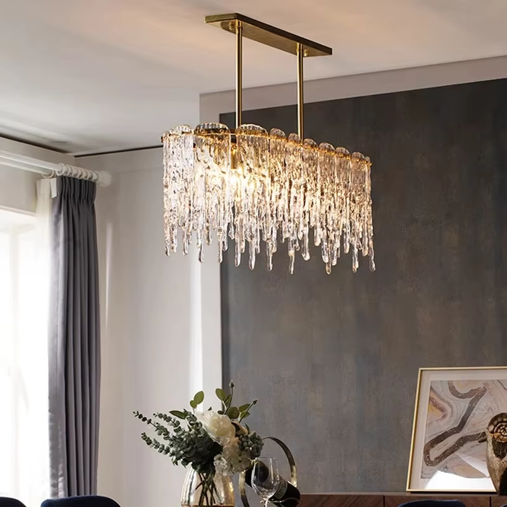This modern light luxury linear chandelier features a gold metal frame paired with icicle-shaped transparent crystal pendants. Light refracts through the crystals to emit a brilliant and soft glow, serving both lighting and decorative purposes, suitable for modern light luxury spaces such as dining rooms and villa living rooms.