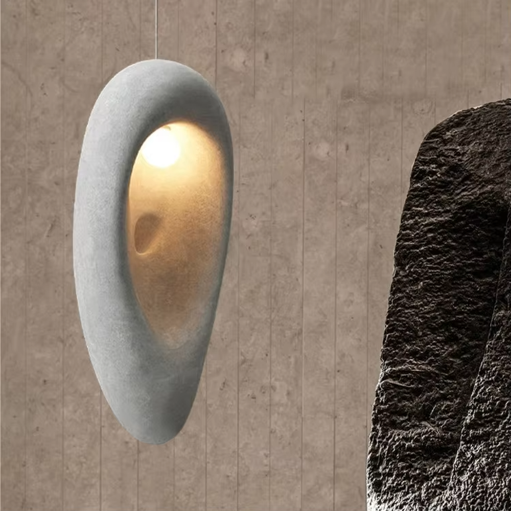 This is a modern wabi-sabi style pebble-shaped pendant lamp, made of frosted cement/resin material with a semi-embedded lighting design, available in colors like gray and green, which has both lighting and decorative functions, suitable for modern minimalist, wabi-sabi style bedrooms, entrances, cafes and other spaces.