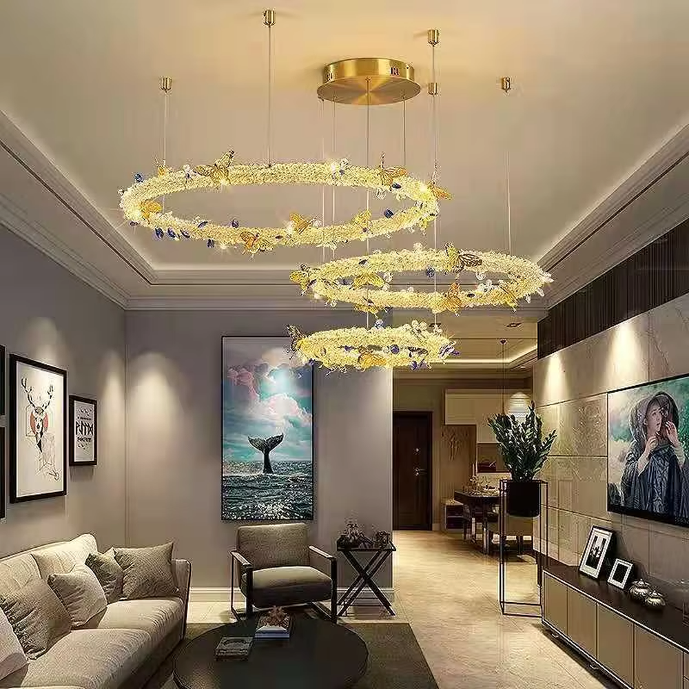 A light luxury and glamorous three-tiered ring chandelier, decorated with crystal gravel, natural blue-veined stone, and gold metal butterflies. Its staggered ring structure resembles flowing cosmic orbits, emitting a brilliant yet soft glow when lit, combining artistic decoration with lighting functionality, ideal for creating a high-end and romantic space atmosphere.