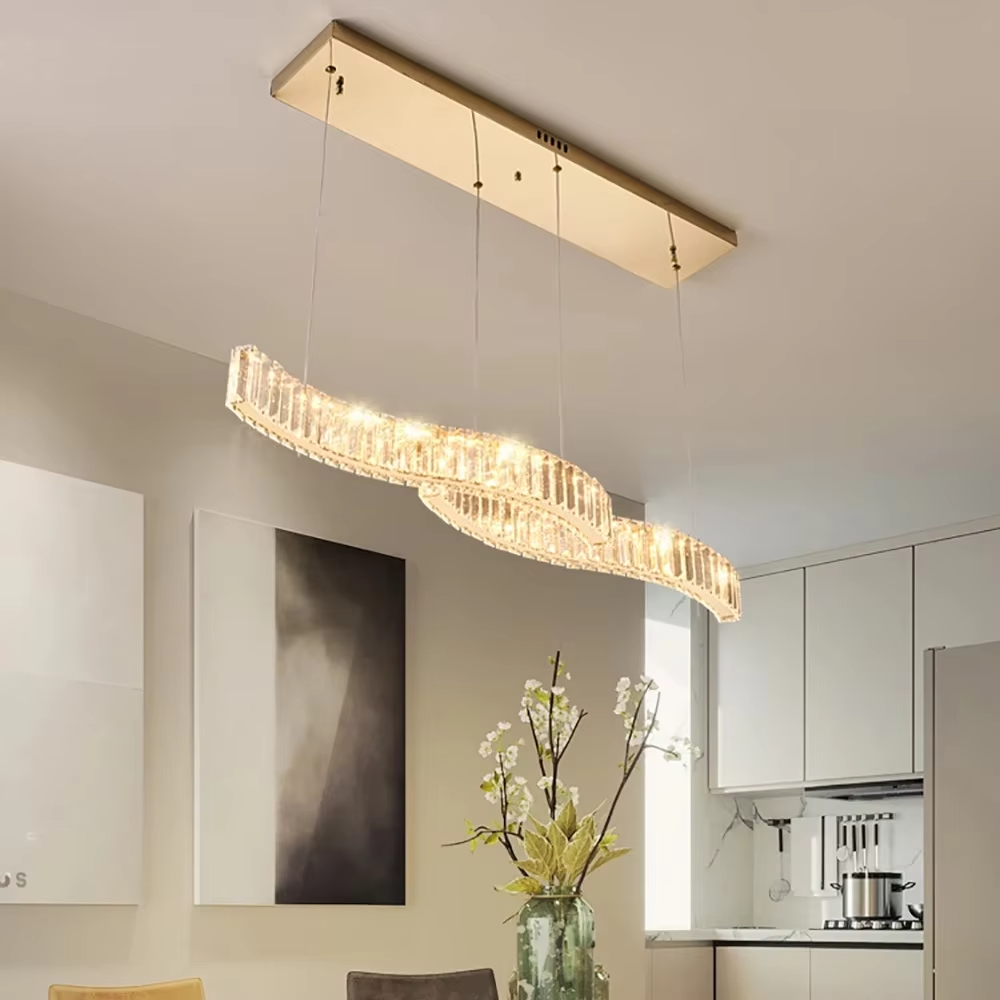 This modern light luxury linear chandelier features a gold metal ceiling plate, paired with faceted crystal strips to create an irregular undulating shape. Light refracts through the crystals to emit a brilliant glow, serving both lighting and decorative purposes, suitable for modern light luxury spaces such as dining rooms and bars.