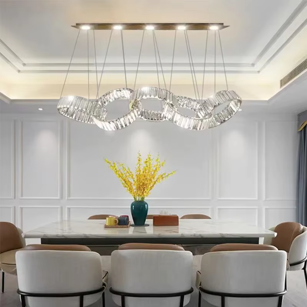 Modern light luxury chain-style ring crystal chandelier, composed of multiple transparent crystal rings connected into a flexible chain shape, paired with metal suspension rods and a long top base, combining decorative and lighting functions, suitable for dining rooms, living rooms, villas and other light luxury style spaces.