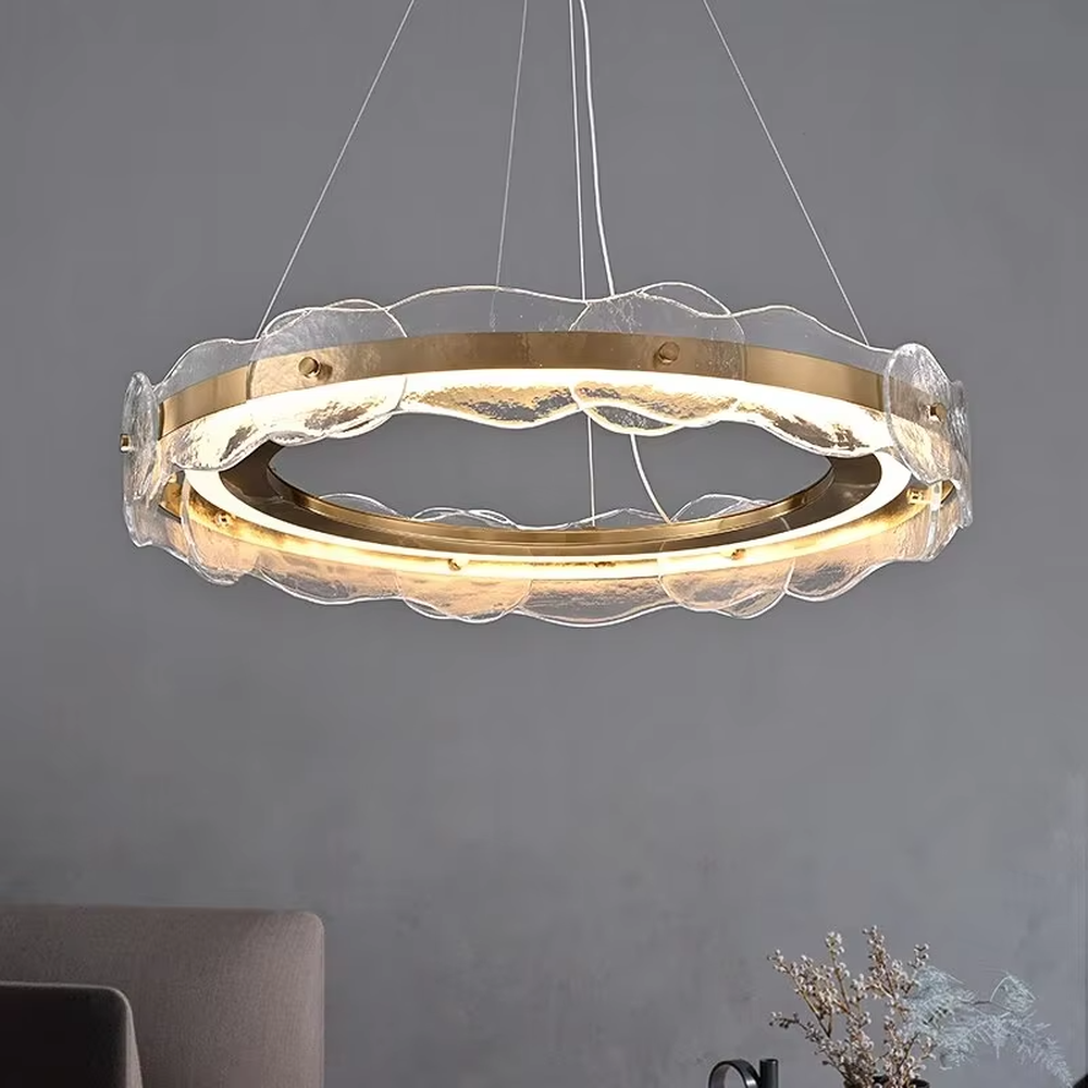 A modern light luxury style double-layer ring chandelier, featuring a gold metal frame paired with transparent glass panels with water ripple texture. It emits a soft and brilliant glow when lit, combining decorative appeal with practical illumination, ideal for creating a high-end and elegant space atmosphere.