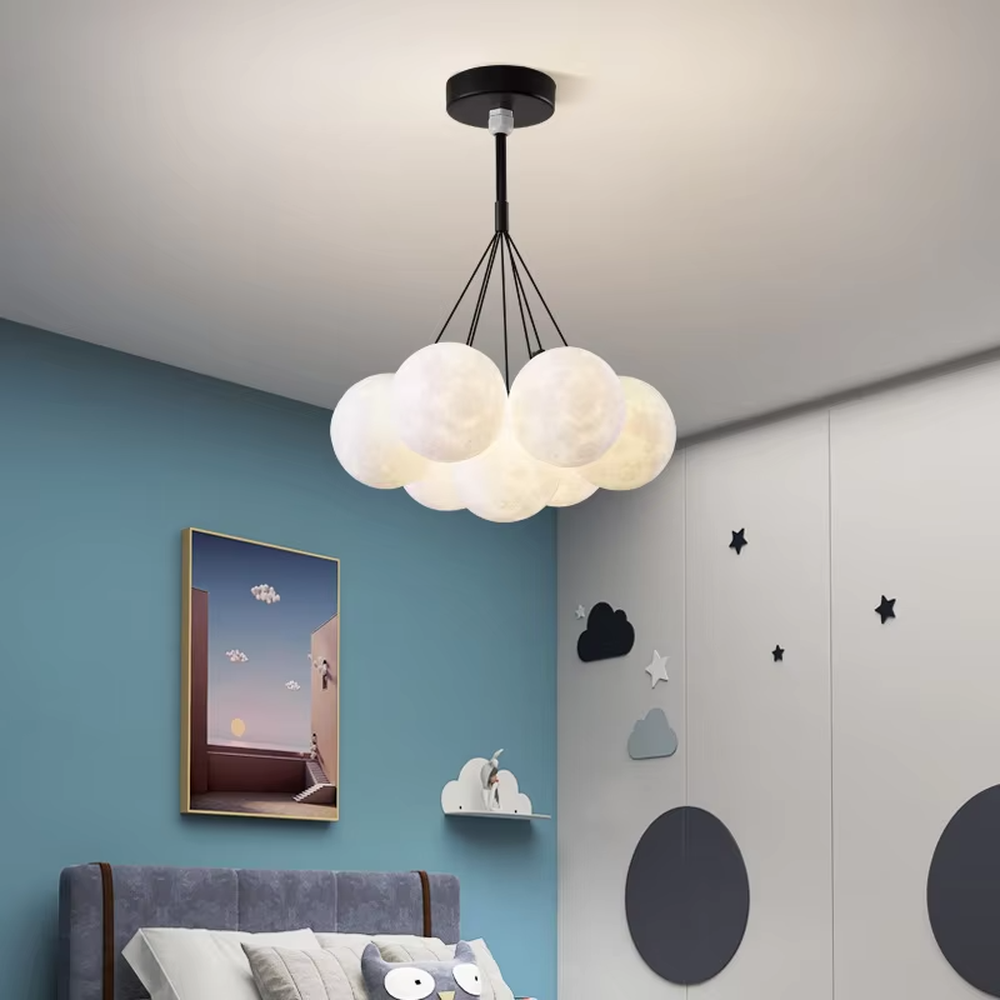 A modern light luxury style moon cluster chandelier, featuring a gold metal frame paired with multiple moon-textured glowing spheres and one colorful nebula sphere. It emits a soft and dreamy glow when lit, combining decorative appeal with practical illumination, ideal for creating a romantic and playful space atmosphere.