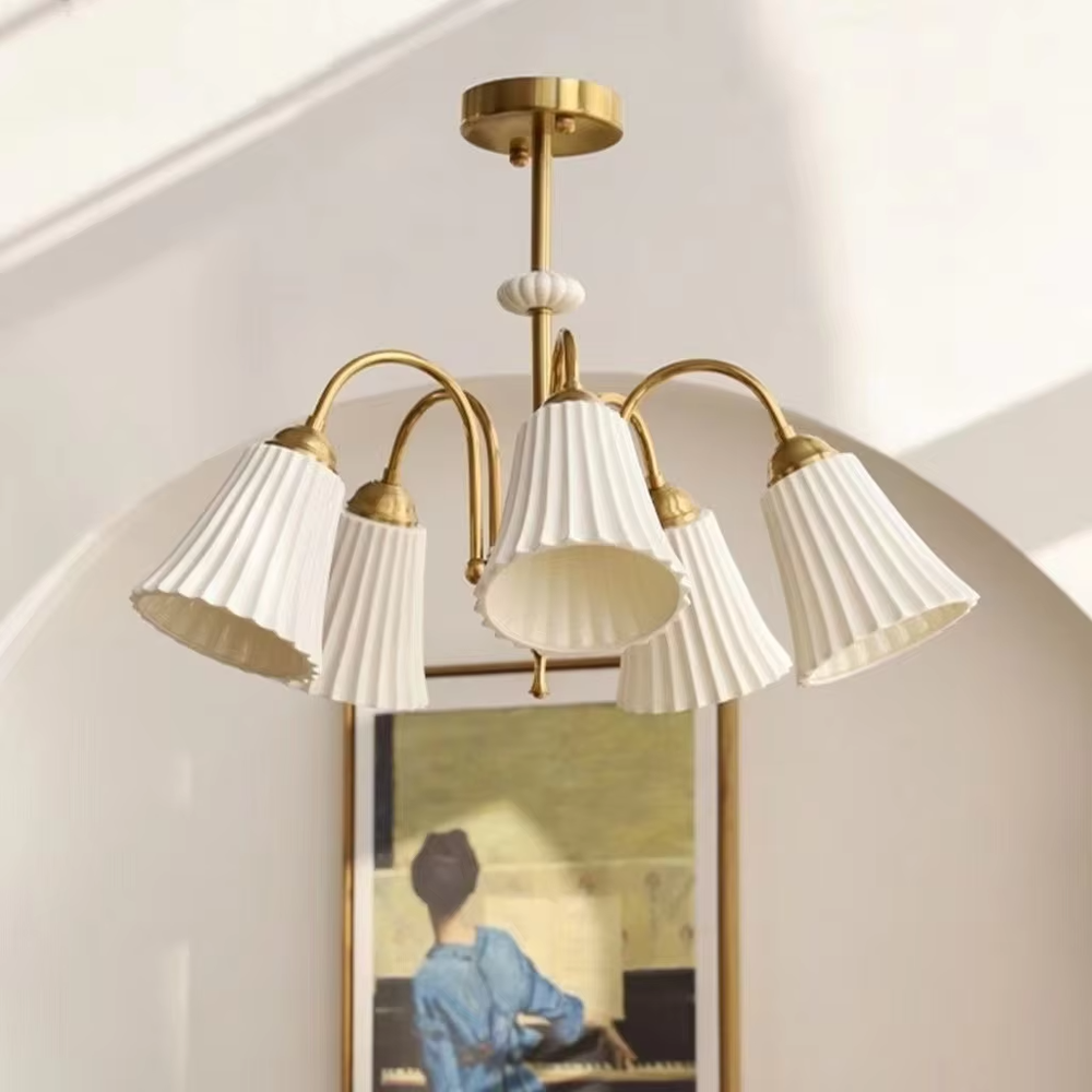 A French retro light luxury style 3-head chandelier, featuring a brass-colored metal frame paired with pleated fabric lampshades. It emits a soft and warm glow when lit, combining decorative appeal with practical illumination, ideal for creating an elegant and romantic space atmosphere.
