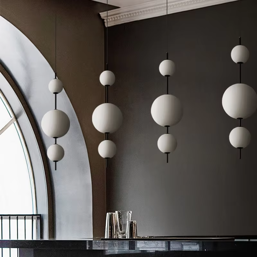 Modern minimalist black-and-white hanging spherical chandelier, with black metal rods paired with milk-white frosted glass ball lampshades of different sizes, shaped like staggered interstellar molecules, featuring soft and uniform light, combining decorative and lighting functions, suitable for dining rooms, bars, commercial spaces and other modern style scenarios.