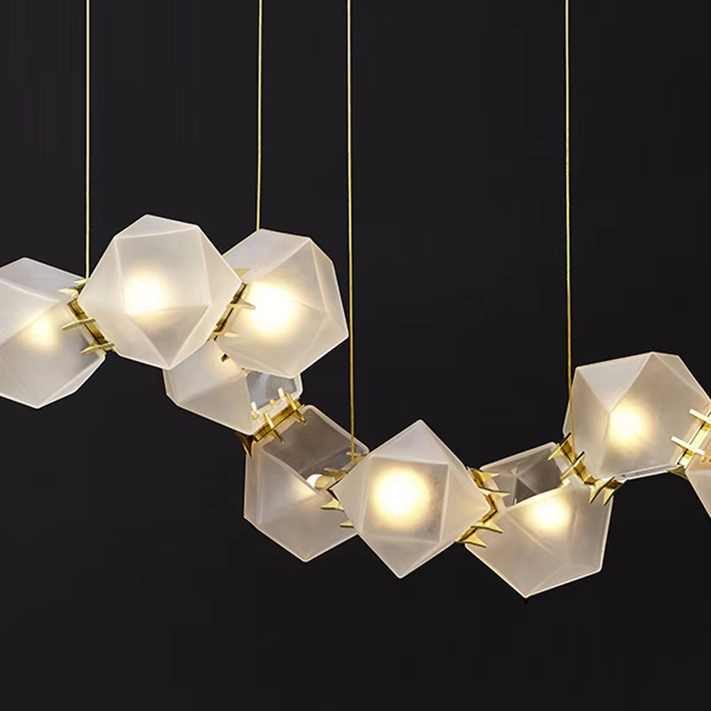A modern light luxury style wave-shaped linear chandelier, suspended by gold wires, paired with frosted geometric polyhedral lampshades. It emits a soft and warm glow when lit, combining decorative appeal with practical illumination, ideal for creating an exquisite and high-end space atmosphere.