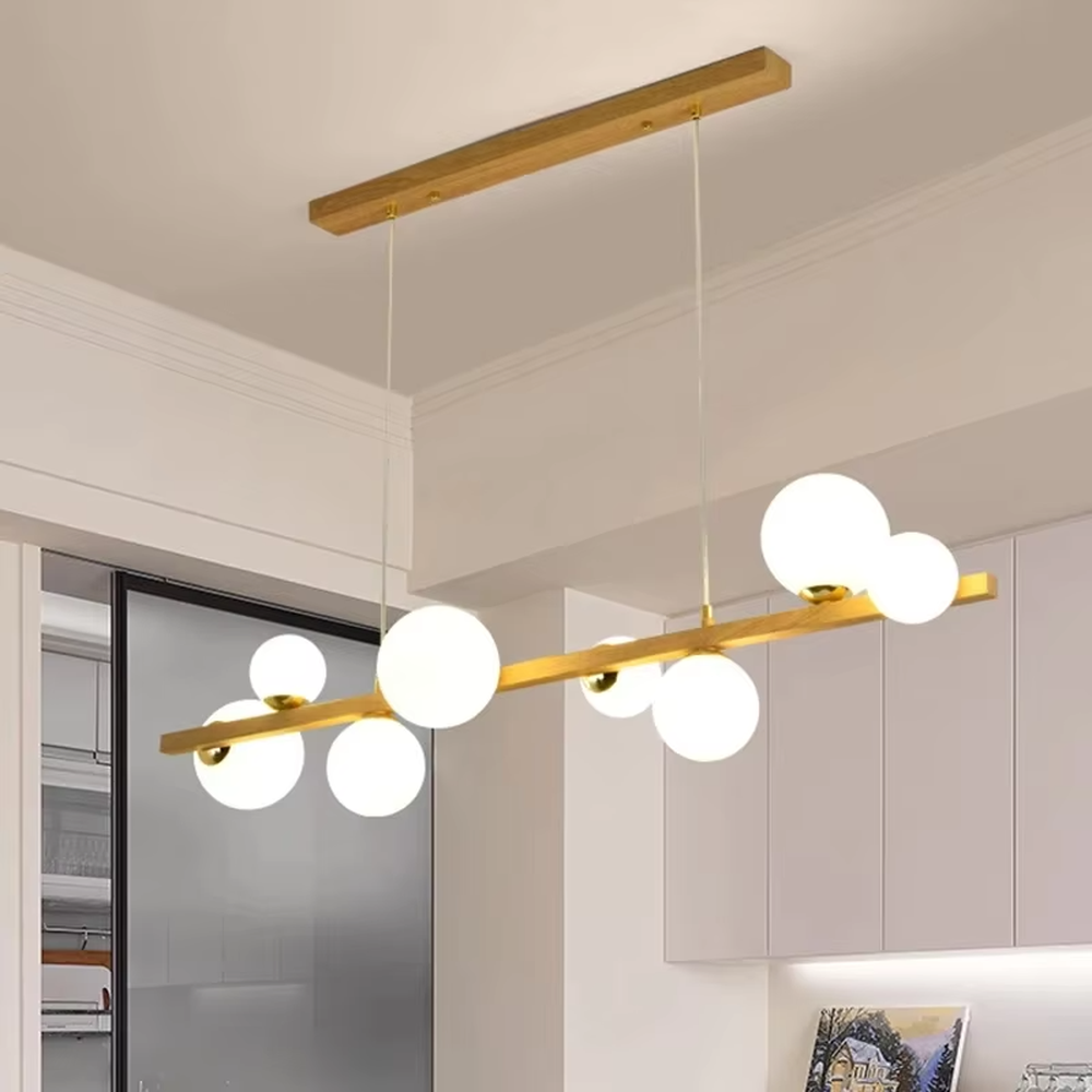Nordic-style gold linear chandelier with a wood-like finish, paired with multiple round milk-white glass ball lampshades. It features a simple and lightweight design, emitting soft and gentle light, serving as a modern home lighting fixture that combines illumination and decoration.
