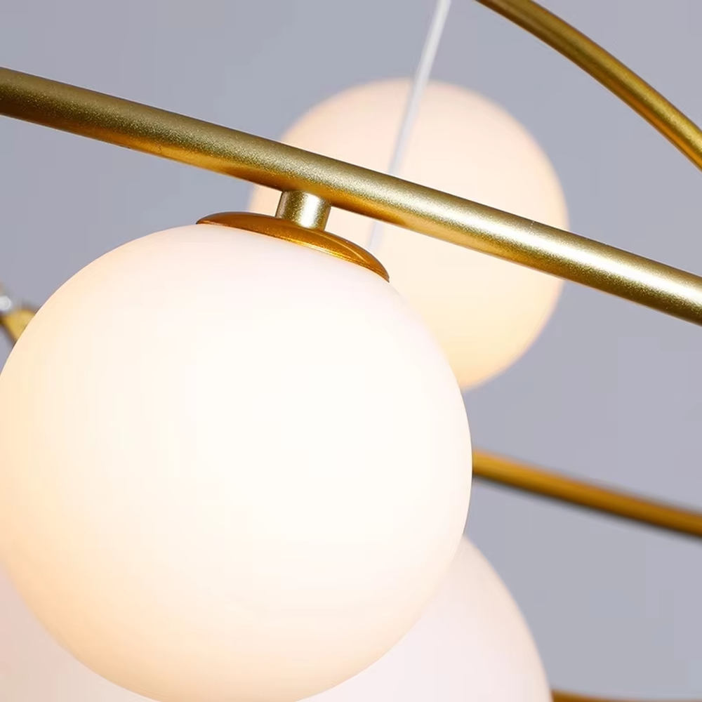 A modern light luxury style planetary orbit chandelier, featuring a gold metal ring frame paired with milky white glass glowing spheres, shaped like planets orbiting a star. It emits a soft and uniform glow when lit, combining decorative appeal with practical illumination, ideal for creating a minimalist and sophisticated space atmosphere.