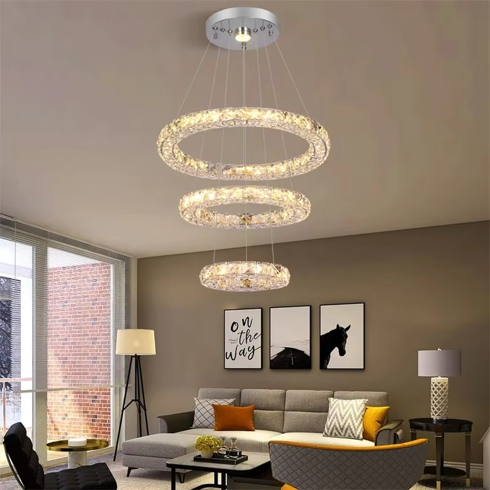 This is a modern light luxury style three-layer ring crystal chandelier, with a silver metal ceiling plate paired with glittering and transparent crystal rings, which has both lighting and decorative functions, suitable for living rooms, dining rooms, villa high-ceiling spaces, etc.