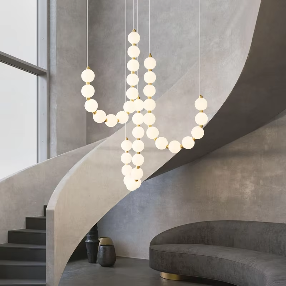 Modern Light Luxury Curved Beaded Chandelier, Milk white spherical lamps connected in a wave shape with gold metal details, serves both lighting and decorative purposes, ideal for duplex stairwells, high-ceiling living rooms, villas and other high-ceiling spaces.
