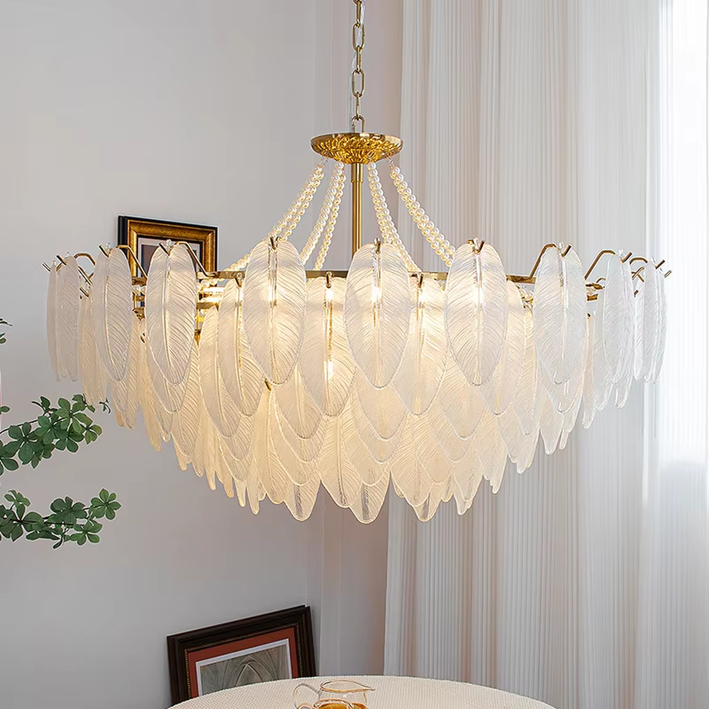 A French light luxury style feather glass chandelier, featuring a gold metal frame paired with double-layer feather-textured glass panels and pearl chain decorations. It emits a soft and warm glow when lit, combining decorative appeal with practical illumination, ideal for creating a romantic and elegant space atmosphere.