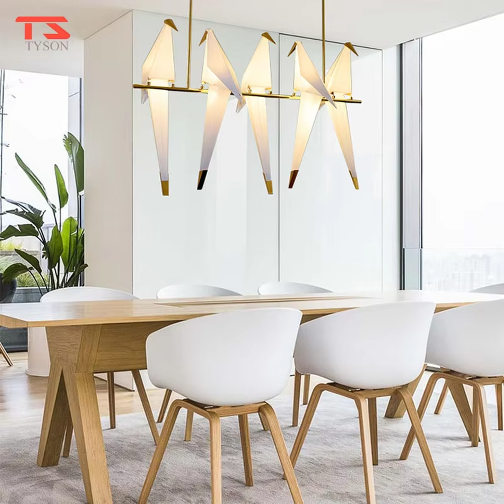 A modern art style linear chandelier in the shape of origami cranes, featuring a gold metal frame paired with translucent paper origami crane lampshades. It emits a soft and warm glow when lit, combining artistic decoration with lighting functionality, ideal for creating a soothing and romantic space atmosphere.
