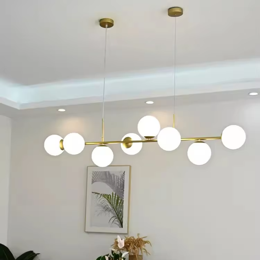 A modern light luxury style linear molecular ball chandelier, featuring a gold metal frame paired with asymmetrically arranged milky white glass glowing spheres. It emits a soft and uniform glow when lit, combining decorative appeal with practical illumination, ideal for creating a minimalist and sophisticated space atmosphere.