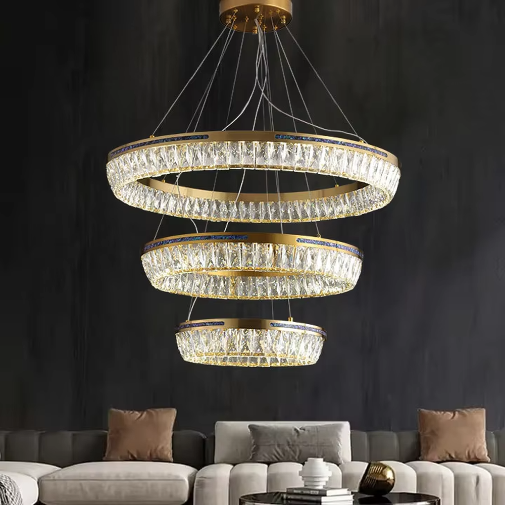 Modern light luxury three-layer ring crystal chandelier, with golden metal frames and transparent crystal lampshades, the staggered suspended shape combines decorative and lighting functions, suitable for high-ceiling living rooms, villas, high-end clubs and other spaces.