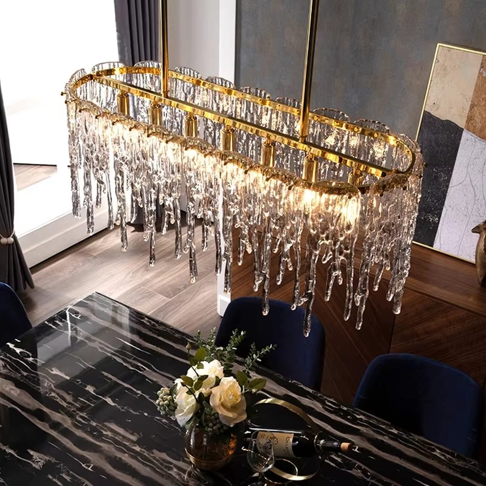 This modern light luxury linear chandelier features a gold metal frame paired with icicle-shaped transparent crystal pendants. Light refracts through the crystals to emit a brilliant and soft glow, serving both lighting and decorative purposes, suitable for modern light luxury spaces such as dining rooms and villa living rooms.