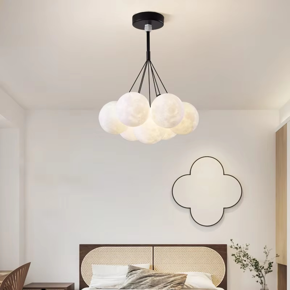 A modern light luxury style moon cluster chandelier, featuring a gold metal frame paired with multiple moon-textured glowing spheres and one colorful nebula sphere. It emits a soft and dreamy glow when lit, combining decorative appeal with practical illumination, ideal for creating a romantic and playful space atmosphere.