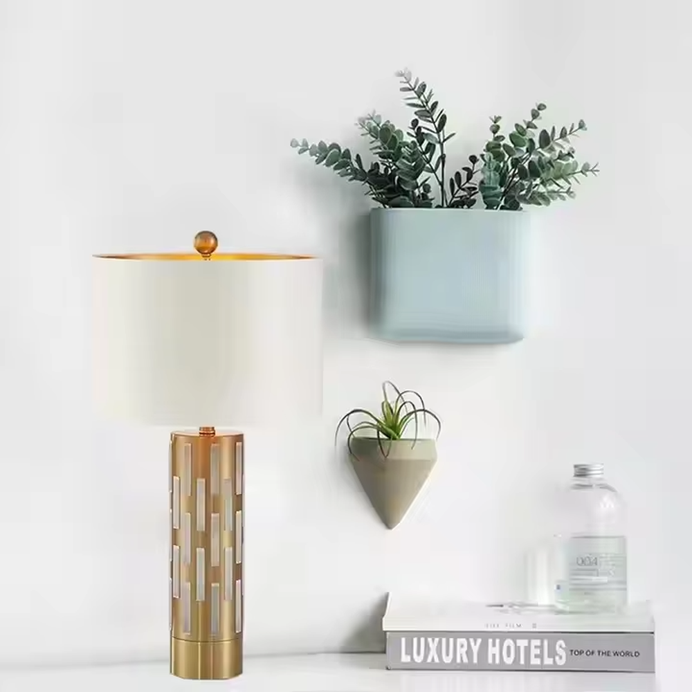 This is a modern minimalist table lamp with a golden base decorated with white vertical strips and a white fabric lampshade, featuring a simple and elegant design. It is used for local desktop lighting and decoration, combining practicality and aesthetics. It is suitable for modern home bedroom bedside tables, living room side tables, high-end hotel guest rooms, luxury apartment living spaces and other places.