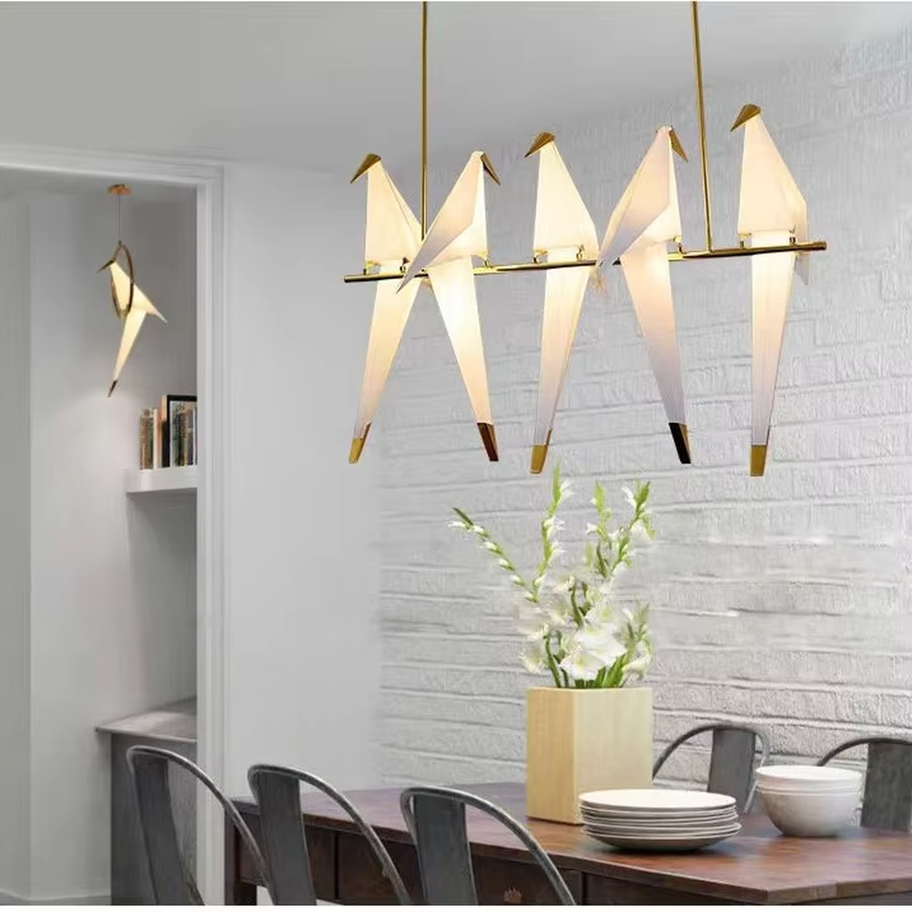 Modern art origami crane chandelier, featuring a gold metal frame paired with white origami crane-shaped lampshades made using paper folding techniques. Its elegant and dynamic lines combine artistry and ambiance, making it a decorative lighting fixture that elevates the space's style.