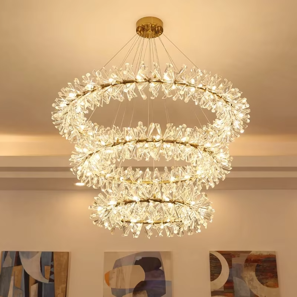 This modern light luxury multi-layer circular chandelier features a gold metal frame, inlaid with transparent snowflake-shaped crystal modules, combined into a three-layer staggered circular shape. When lit, light refracts through the crystal to emit a brilliant and soft glow, combining an ethereal feel with an ambient atmosphere. Ideal for living rooms, dining rooms, light luxury apartments, and other spaces, it adds a dreamy and exquisite touch to modern minimalist or French light luxury home environments.
