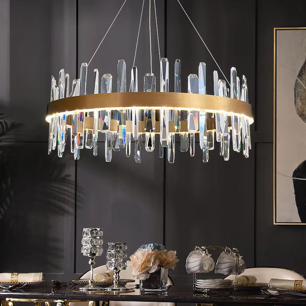 This modern light luxury circular crystal chandelier features a gold metal frame, with transparent crystal strips of varying lengths hanging down to form a staggered circular shape. When lit, light refracts through the crystal to emit a brilliant and dynamic glow, combining an exquisite texture with an ambient atmosphere. Ideal for dining rooms, living rooms, light luxury apartments, and other spaces, it adds an exquisite and sophisticated touch to modern minimalist or light luxury home environments.