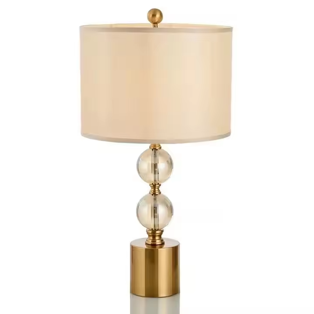 This is a luxury-style table lamp with a golden base, transparent glass spherical body, and beige fabric lampshade. It features a simple and elegant design with excellent texture. It is used for local desktop lighting and decoration, creating a luxurious and warm ambiance. It is suitable for luxury-style home bedroom bedside tables, high-end hotel guest rooms, modern apartment living spaces and other places.