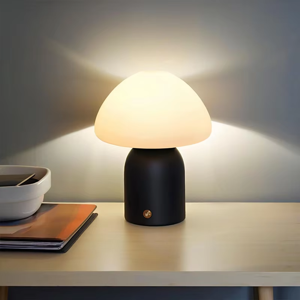 This is a minimalist mushroom-shaped table lamp with a white rounded mushroom lampshade and a simple base, featuring a fresh and cute design with a warm ambiance. It is used for local desktop lighting and decoration, creating a minimalist and warm atmosphere. It is suitable for Nordic-style home bedrooms, children's rooms, minimalist office spaces and other places.