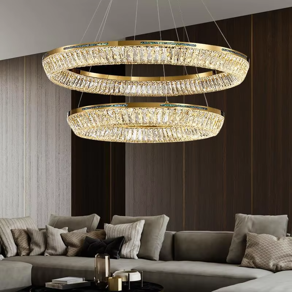 This modern light luxury multi-layered ring crystal chandelier features a gold metal frame, with each ring inlaid with transparent long crystals arranged in concentric circles. When lit, light refracts through the crystal to emit a brilliant and luxurious glow, combining layered design with an ambient atmosphere. Ideal for high-ceiling living rooms, villa foyers, hotel lobbies, and other spaces, it adds an elegant and exquisite touch to modern light luxury or European-style luxury environments.