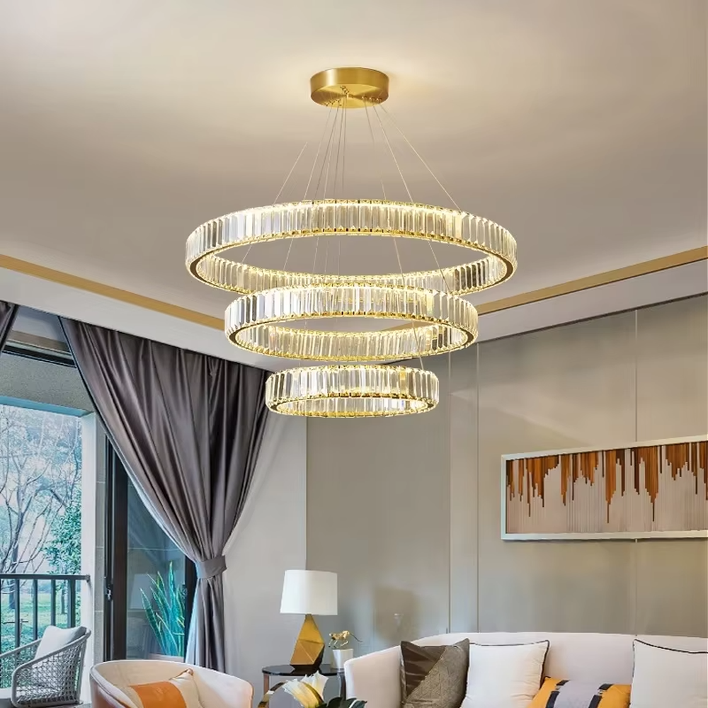 This modern light luxury multi-ring crystal chandelier consists of multiple crystal rings of varying sizes suspended in a staggered layout, each inlaid with transparent long crystals and adjustable via gold suspension wires. When lit, light refracts through the crystal to emit a brilliant and soft glow, combining layered design with an ambient atmosphere. Ideal for high-ceiling living rooms, villa foyers, hotel lobbies, or duplex spaces, it adds an exquisite and sophisticated touch to modern light luxury or minimalist environments.