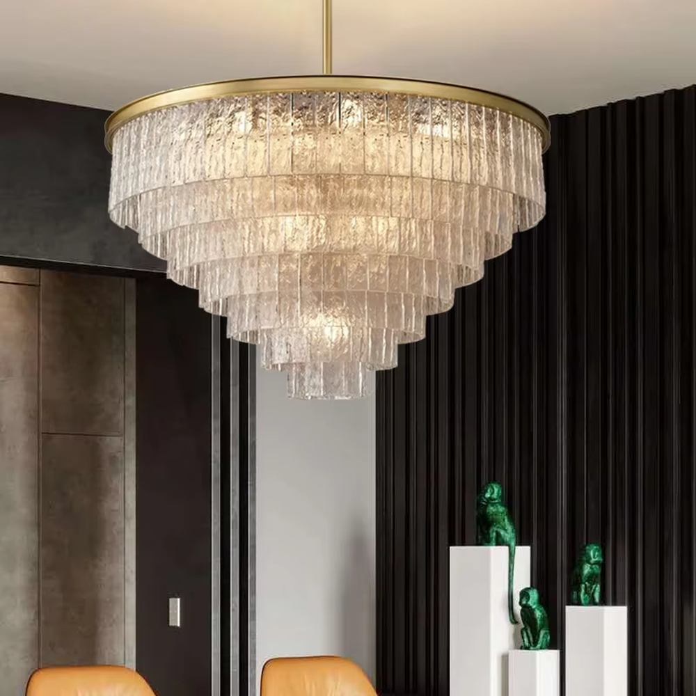 This modern light luxury layered conical chandelier features a gold metal top frame, with multiple layers of textured glass strips hanging down to form a conical layered shape. When lit, light refracts through the glass to emit a brilliant and soft glow, combining a luxurious texture with an ambient atmosphere. Ideal for high-ceiling living rooms, villas, light luxury apartments, and other spaces, it adds an exquisite and sophisticated touch to modern minimalist or light luxury home environments.
