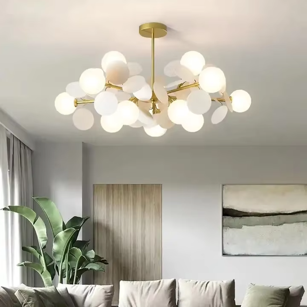 Modern light luxury firefly chandelier, featuring a radial branch frame in brass metal paired with clustered milk-white frosted glass balls to form a starburst shape. It emits soft and translucent light, combining a dreamy feel and elegant ambiance, making it a high-end decorative lighting fixture that elevates the space's style.