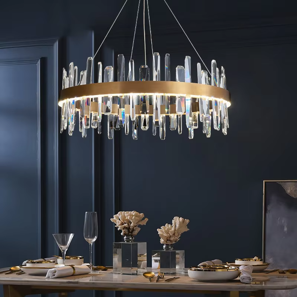 This modern light luxury circular crystal chandelier features a gold metal frame, with transparent crystal strips of varying lengths hanging down to form a staggered circular shape. When lit, light refracts through the crystal to emit a brilliant and dynamic glow, combining an exquisite texture with an ambient atmosphere. Ideal for dining rooms, living rooms, light luxury apartments, and other spaces, it adds an exquisite and sophisticated touch to modern minimalist or light luxury home environments.