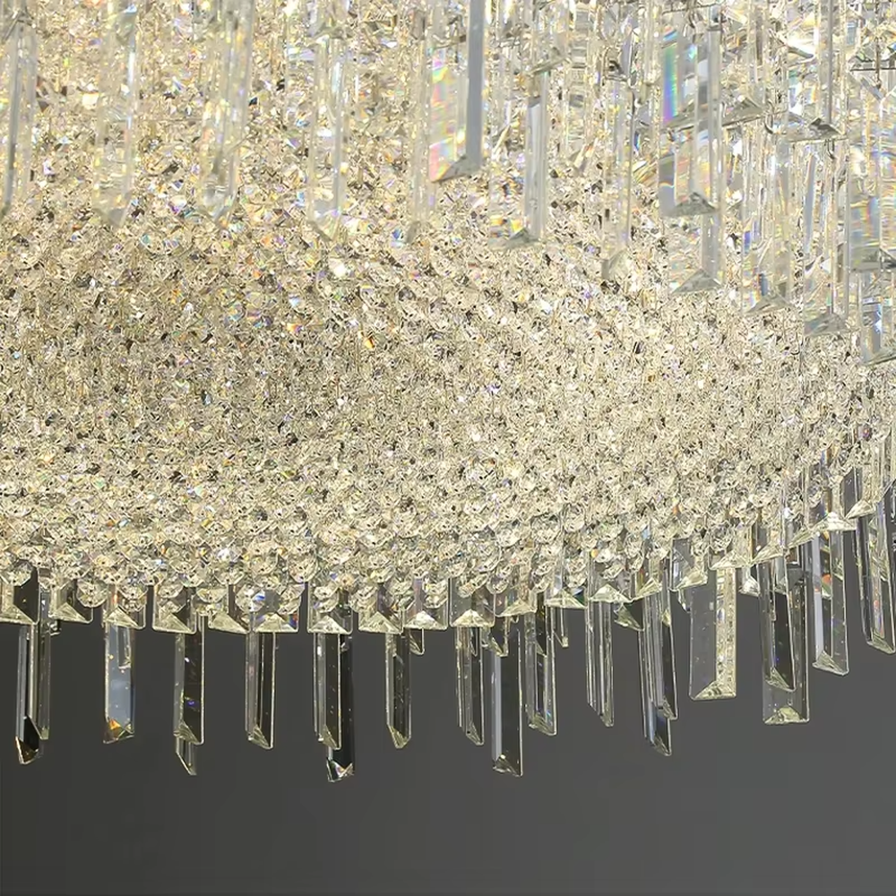 This modern light luxury square crystal chandelier features a silver metal frame, with dense transparent long crystals hanging down to form a square shape. When lit, light refracts through the crystal to emit a brilliant and soft glow, combining an exquisite texture with an ambient atmosphere. Ideal for bedrooms, dining rooms, light luxury apartments, and other spaces, it adds an exquisite and sophisticated touch to modern minimalist or light luxury home environments.