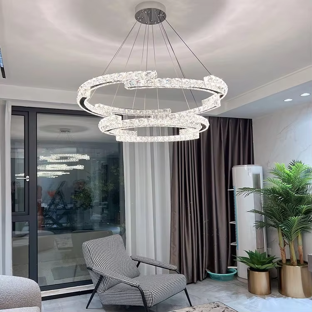 This modern light luxury double-ring interwoven crystal chandelier features a silver metal base, inlaid with transparent crystals to create a dynamic double-ring interwoven shape. When lit, light refracts through the crystal to emit a brilliant and dynamic glow, combining a futuristic feel with an ambient atmosphere. Ideal for living rooms, dining rooms, light luxury apartments, and other spaces, it adds an exquisite and sophisticated touch to modern minimalist or light luxury home environments.