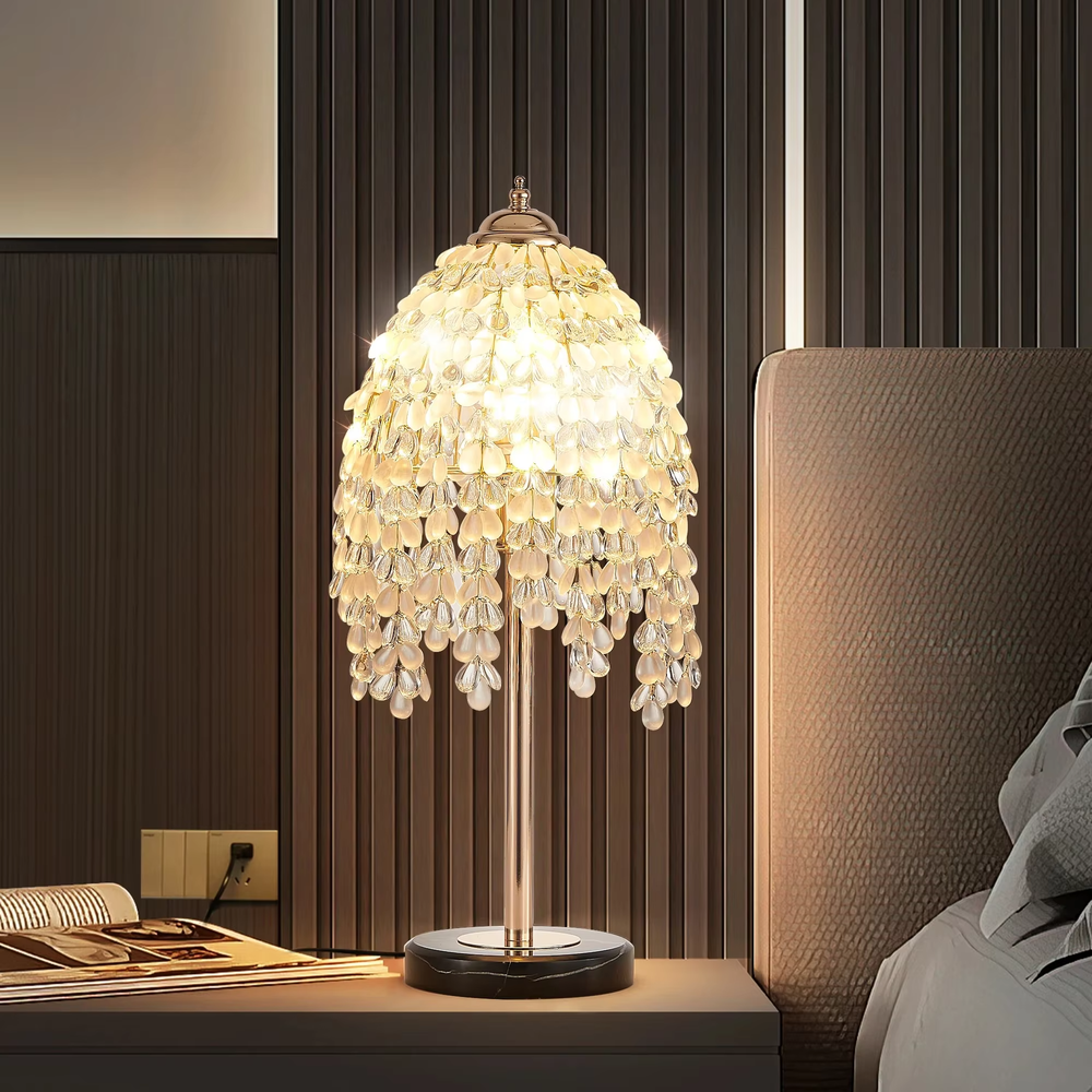 This is a luxury shell crystal table lamp with multi-layer shell-shaped crystal pendants, a golden bracket, and a black marble base, featuring a brilliant and luxurious design. It is used for local desktop lighting and decoration, creating a high-end luxurious atmosphere. It is suitable for luxury-style home bedroom bedside tables, high-end hotel guest rooms, European-style soft decoration spaces and other places.
