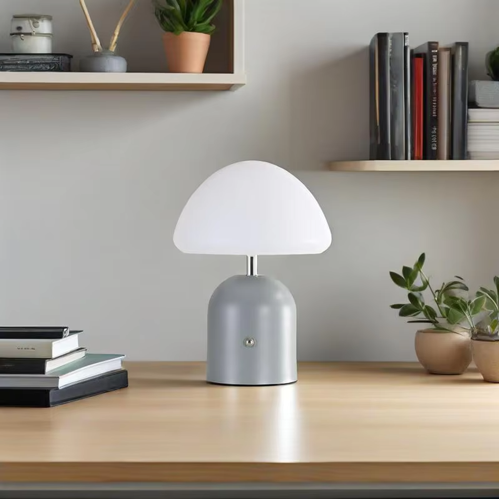 This is a minimalist mushroom-shaped table lamp with a white rounded mushroom lampshade and a simple base, featuring a fresh and cute design with a warm ambiance. It is used for local desktop lighting and decoration, creating a minimalist and warm atmosphere. It is suitable for Nordic-style home bedrooms, children's rooms, minimalist office spaces and other places.