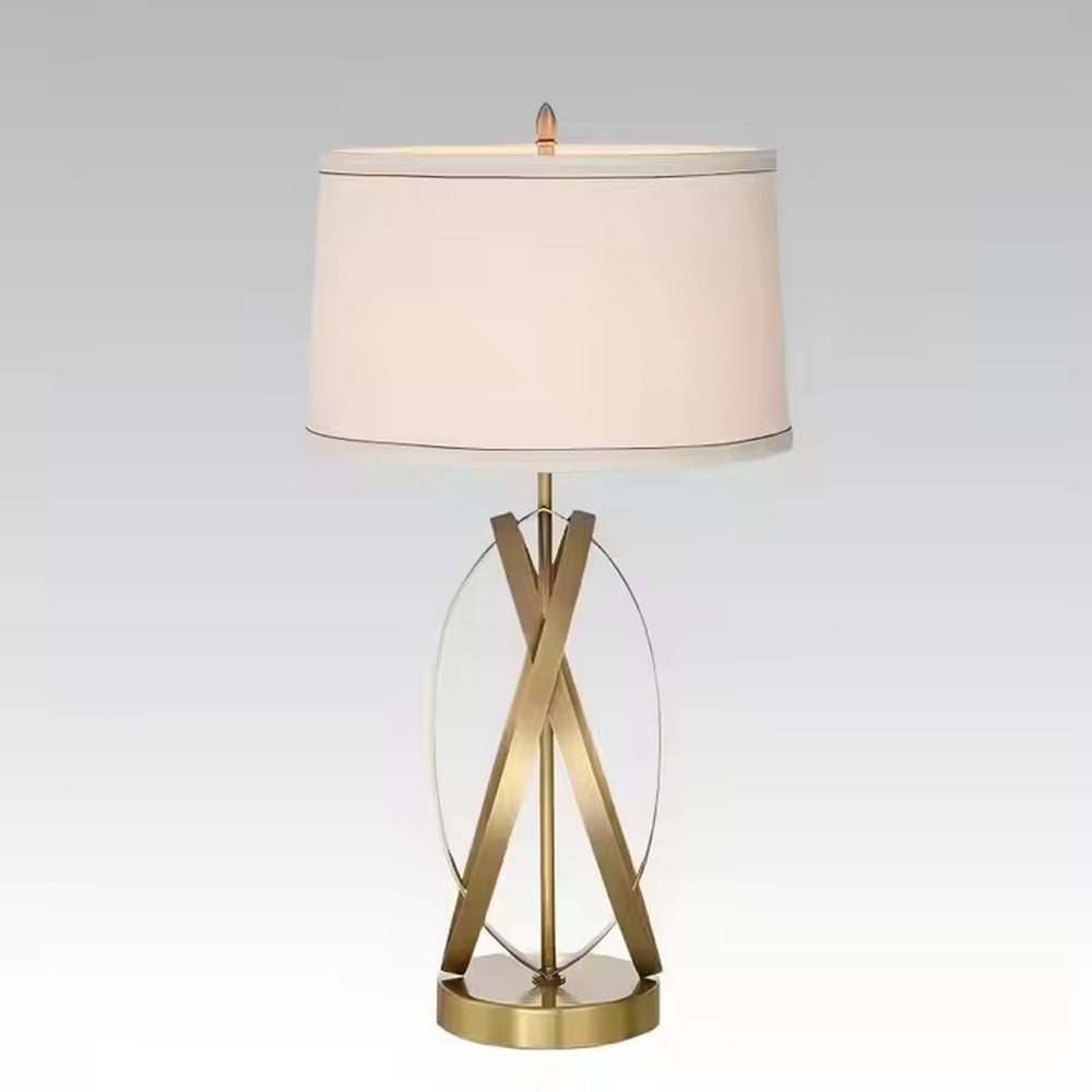 This is a luxury-style table lamp with golden crossed metal brackets and a beige fabric lampshade. It features a simple and elegant design with excellent texture. It is used for local desktop lighting and decoration, creating a luxurious and warm ambiance. It is suitable for luxury-style home bedroom bedside tables, high-end hotel guest rooms, modern office spaces and other places.